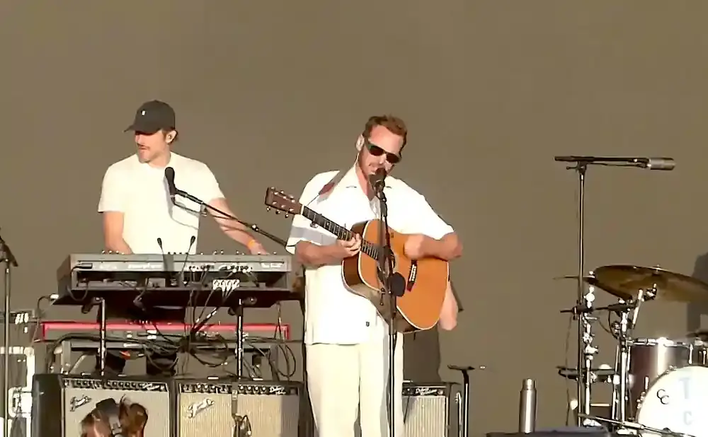 Musicians perform on stage; one plays guitar and sings, another plays a keyboard.