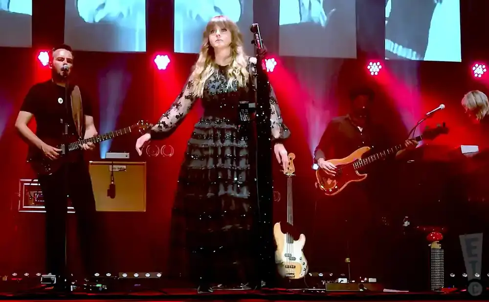 Singer Taylor Swift in a black sequined dress performs on stage with a band.