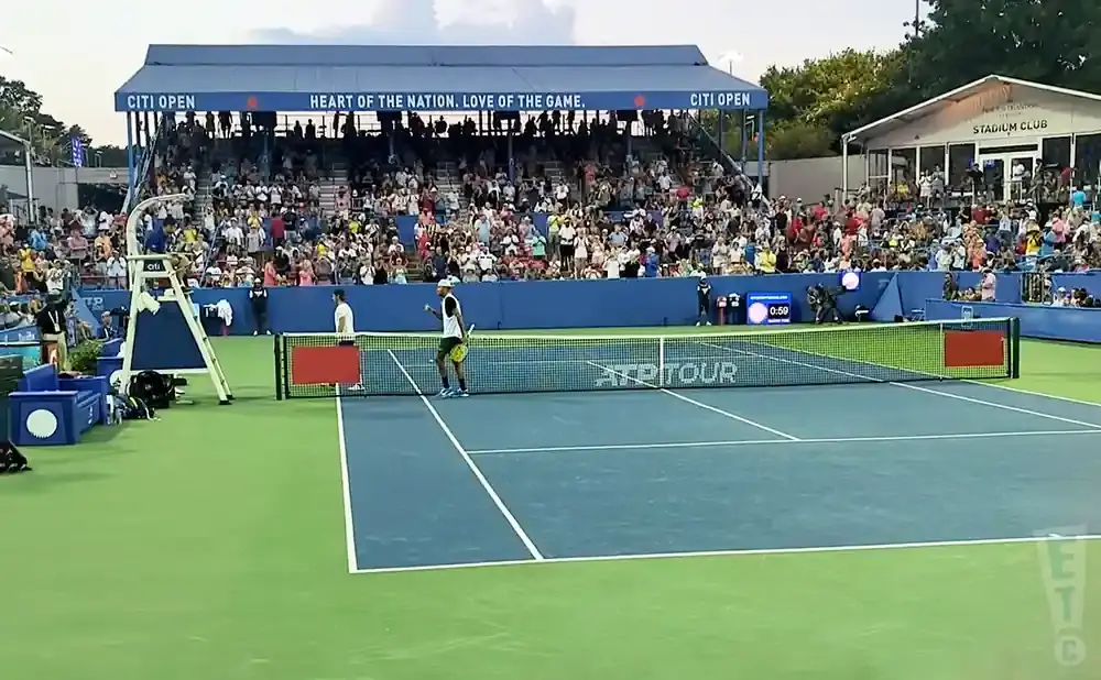 Tennis match at Citi Open with players on court and spectators in bleachers.