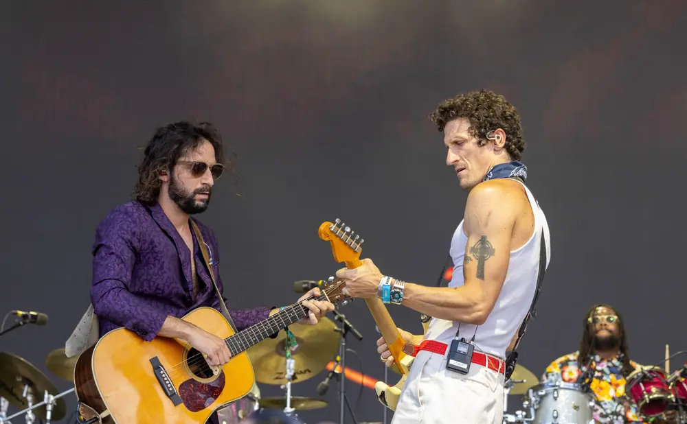 Musicians play guitar and drums on stage.