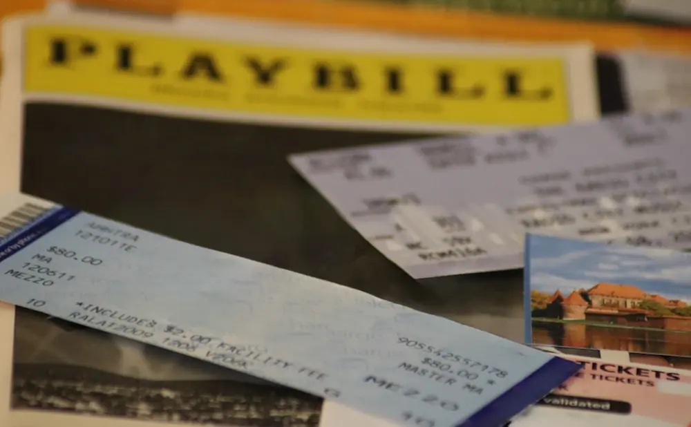 Playbill and tickets on a table, with a postcard of a castle in the foreground.