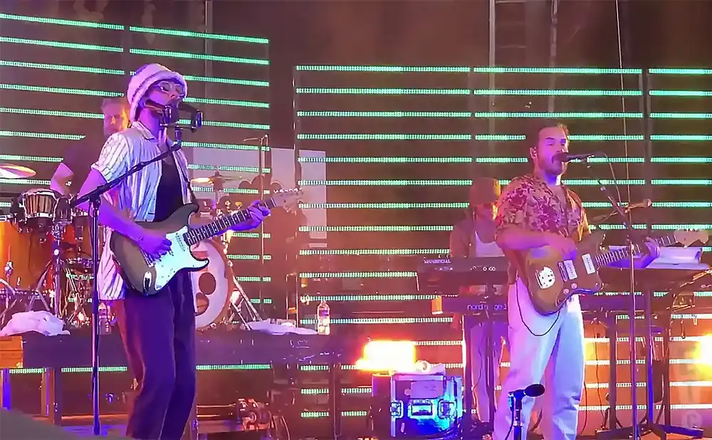 A band performs on stage with bright green lights behind them.