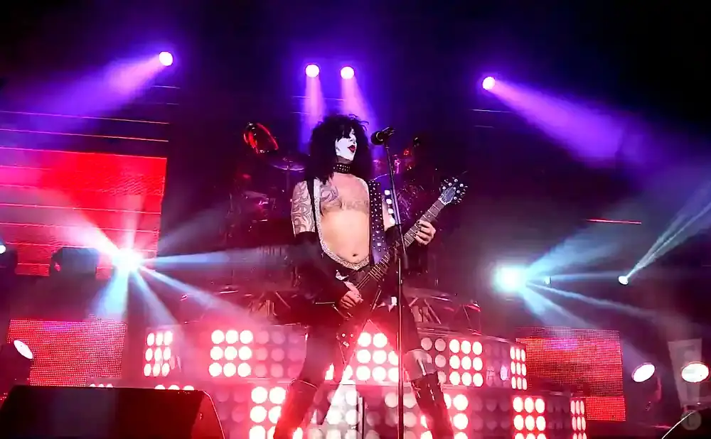 Paul Stanley of KISS performs on stage with a guitar and elaborate makeup.