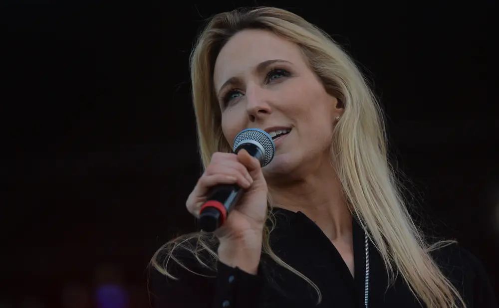 Woman with blonde hair speaking into a microphone.