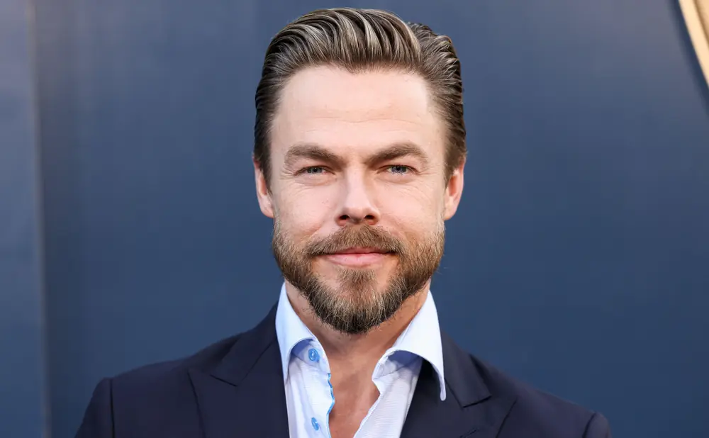 A man with styled hair and a beard smiles at the camera.