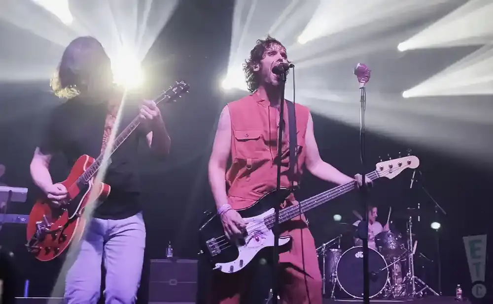 Band playing music on stage with bright lights.