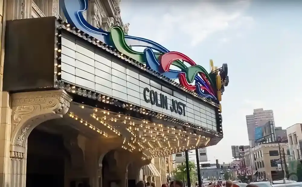 Marquee for Colin Jost with colorful neon accents above a marquee with a grid of lights.