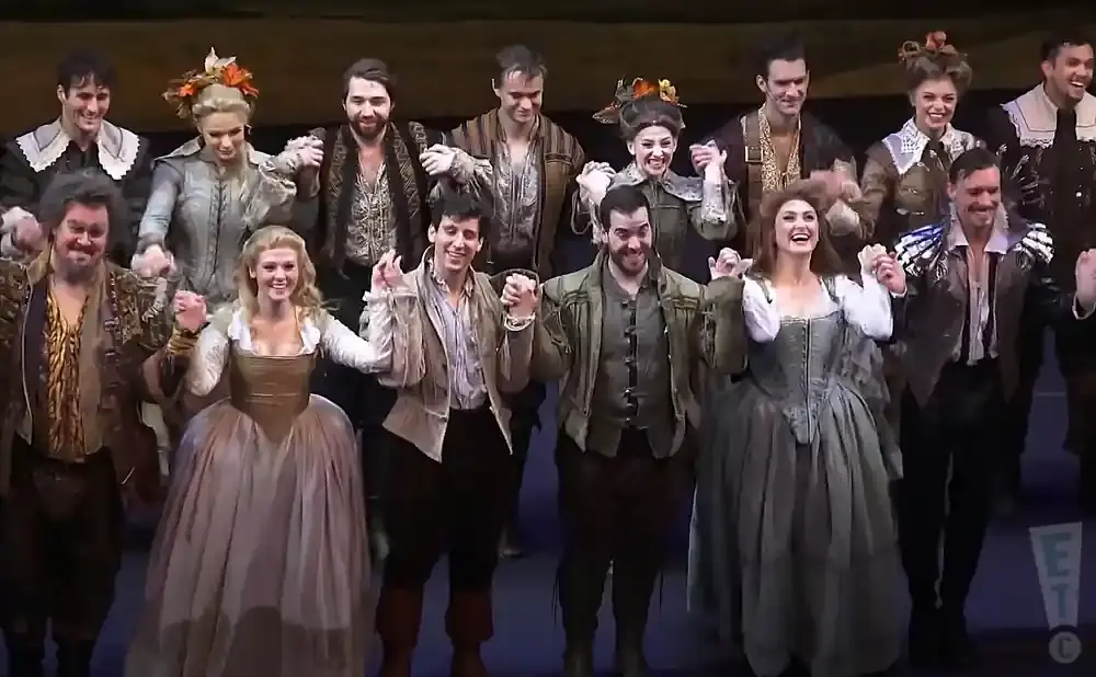 A theater cast bows to the audience, holding hands.