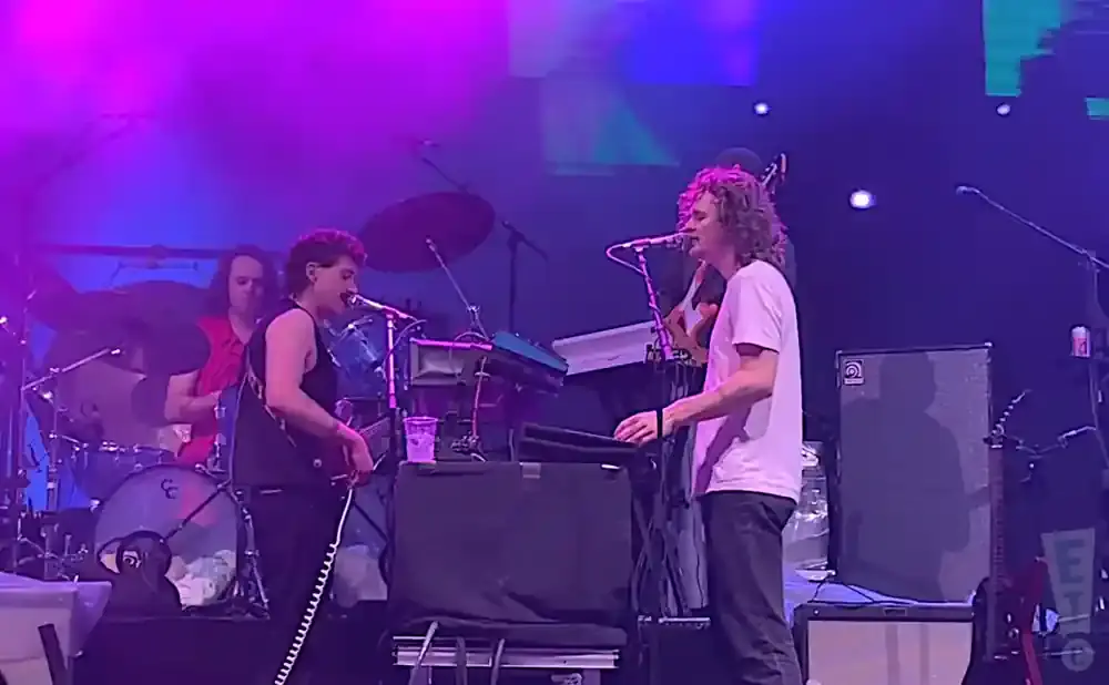 A band performs on a dimly lit stage under purple and blue lights.