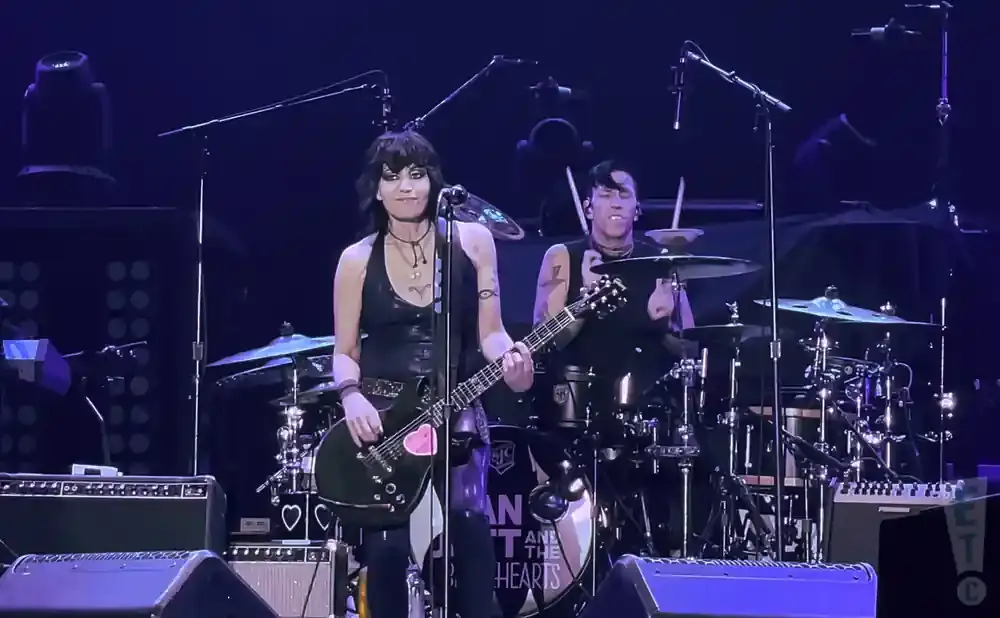 Joan Jett and the Blackhearts performing live on stage with Joan Jett on guitar and a drummer in the background.