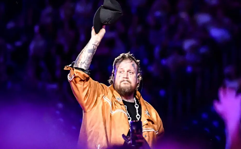 Rapper Jelly Roll raises his hat to the crowd during a performance.