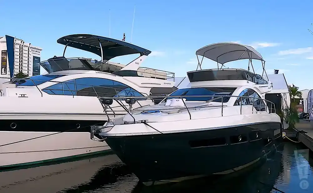 Two luxury yachts docked side-by-side, with a clear blue sky above.
