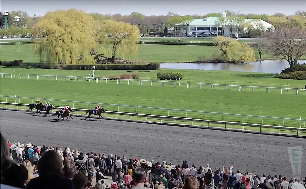 Horse race at Belmont Park with spectators in the foreground.