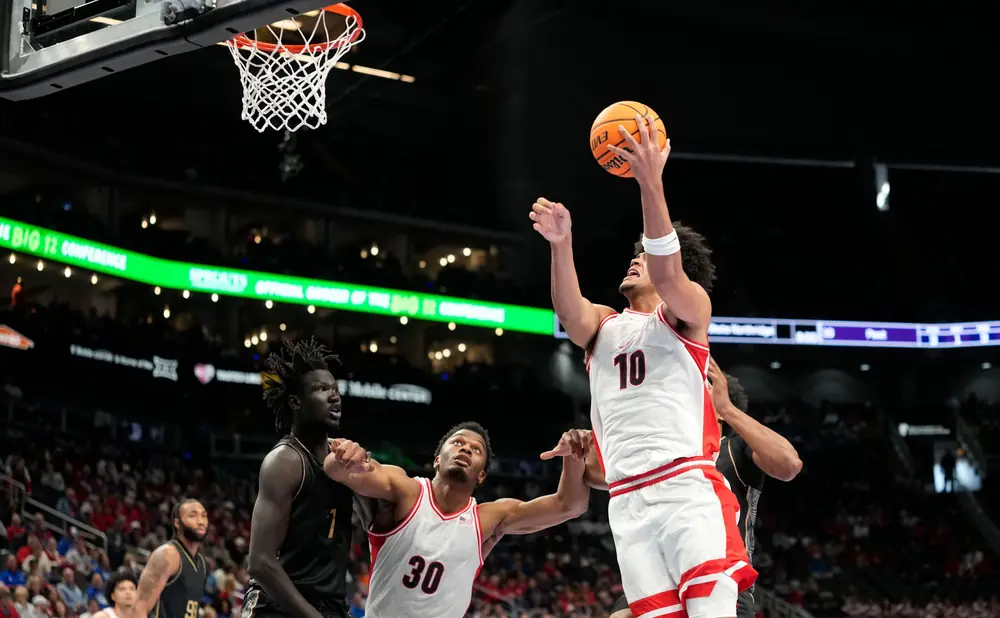 Basketball player in white jersey with number 10 dunks the ball as defenders reach for it.
