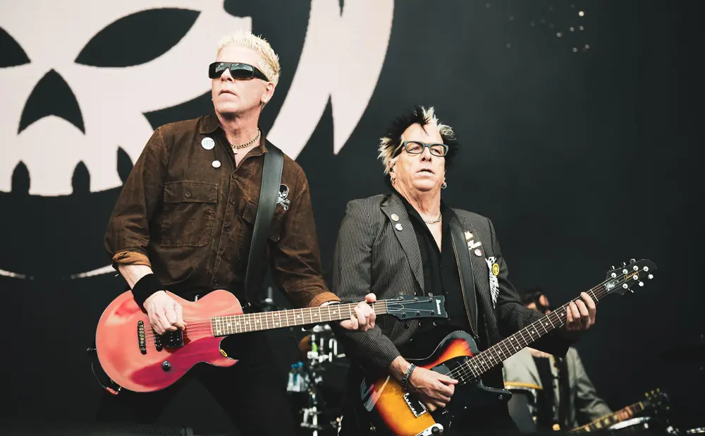 Dexter Holland and Noodles of The Offspring perform on stage with guitars.