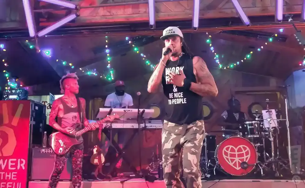 A band performs on stage with a guitarist, singer, and drummer.