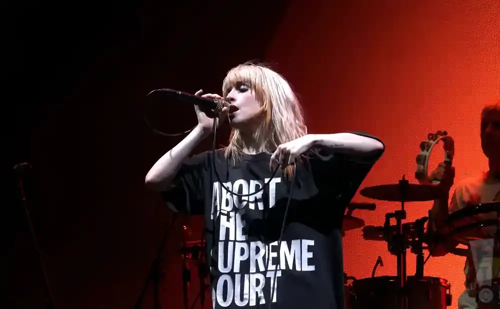 Singer performs with a microphone while wearing a t-shirt that says 