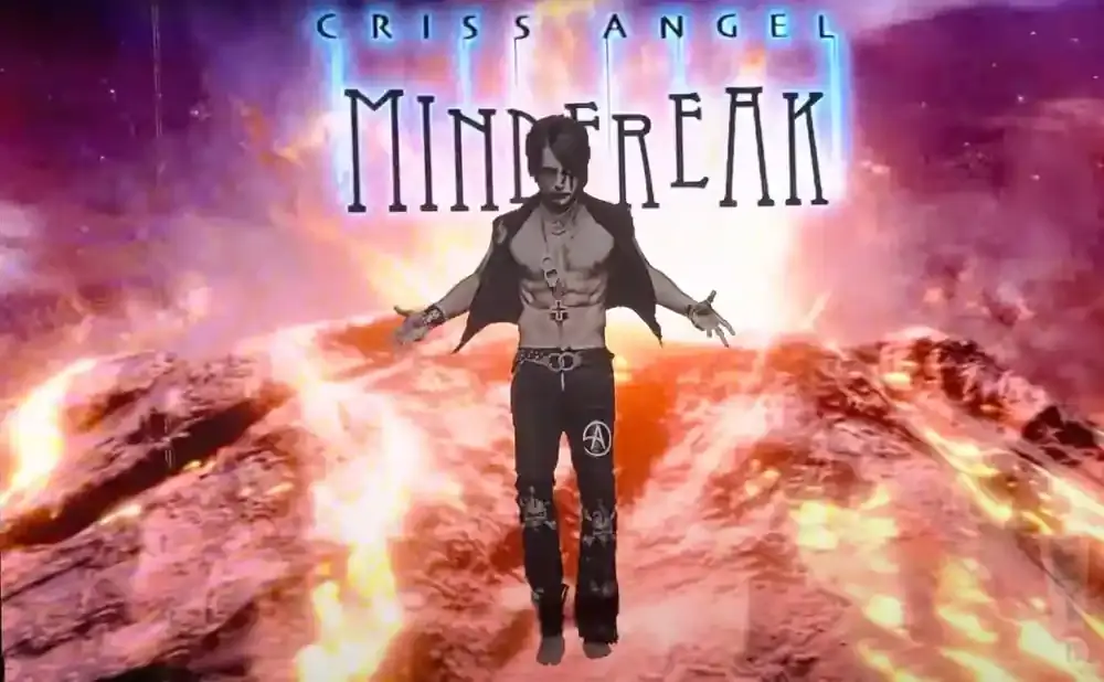 Criss Angel, shirtless and in black pants, stands with arms outstretched in front of a 