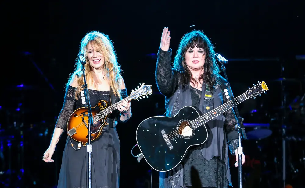 Two women on stage, one plays a mandolin and the other plays a guitar decorated with stars.