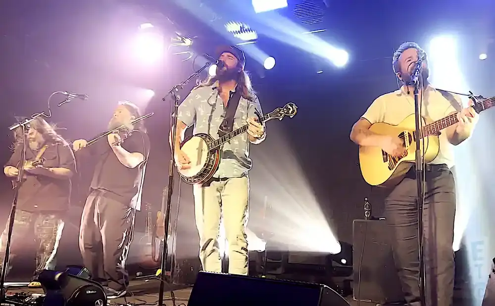 A band performs on stage with bright lights and fog.