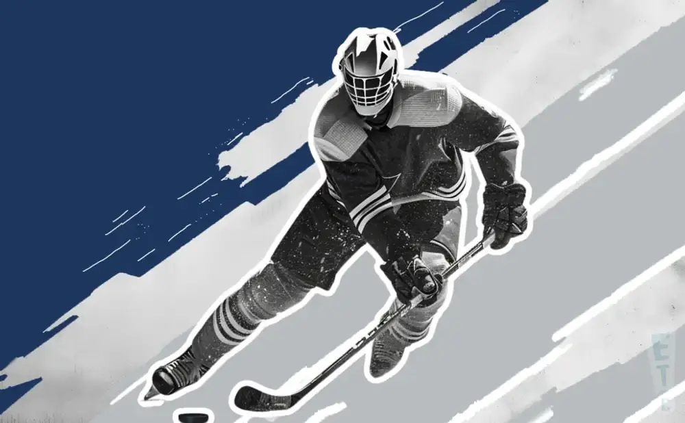 A hockey player in a black and white uniform skates with a puck and stick.