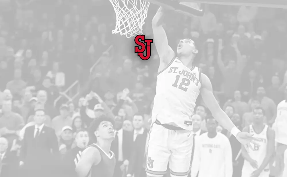 Basketball player in St. John's jersey #12 dunks the ball as the 