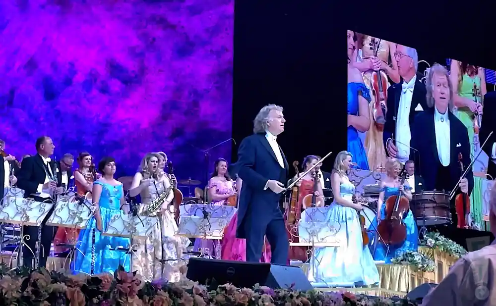 andre rieu performing live on stage with an orchestra