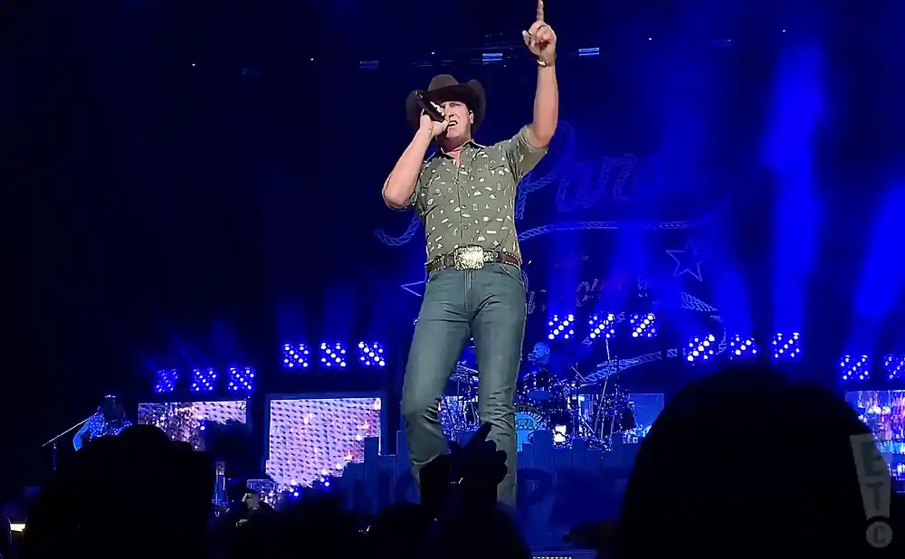 jon pardi performing on stage in a green shirt and cowboy hat