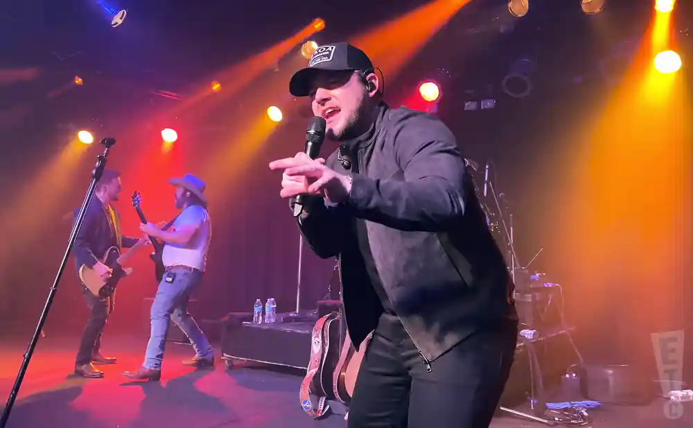 kameron marlowe singing on stage with two electric guitarists behind him
