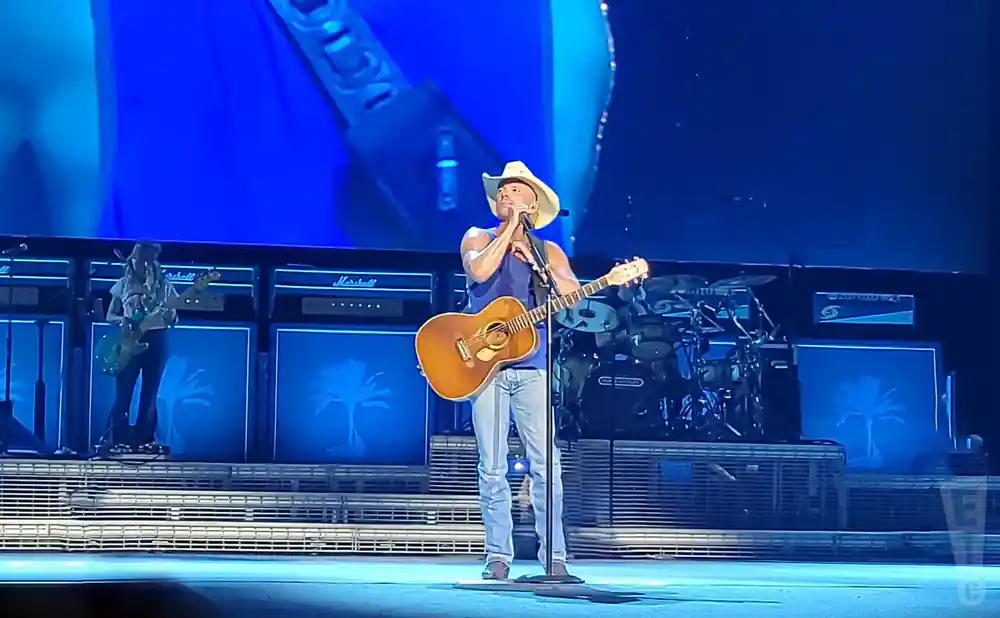 kenny chesney performing on stage holding a guitar