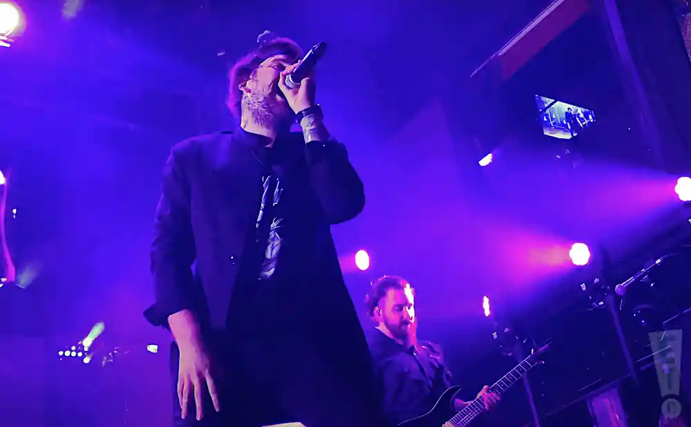 beartooth singer and electric guitarist playing in purple light