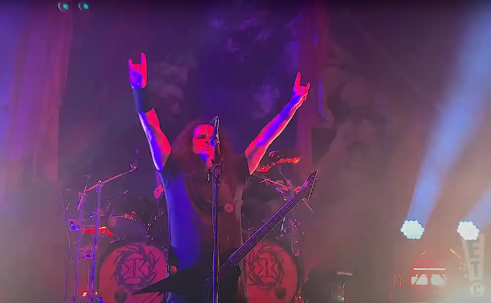 kreator lead singer live on stage holding electric guitar
