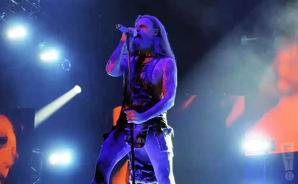 rob zombie holding the mic stand under blue and orange light