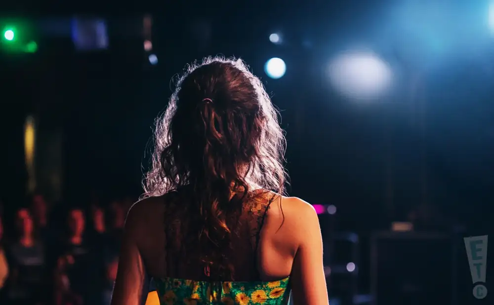 a rear view photo of abigail dowd performing a concert on stage to a lively audience