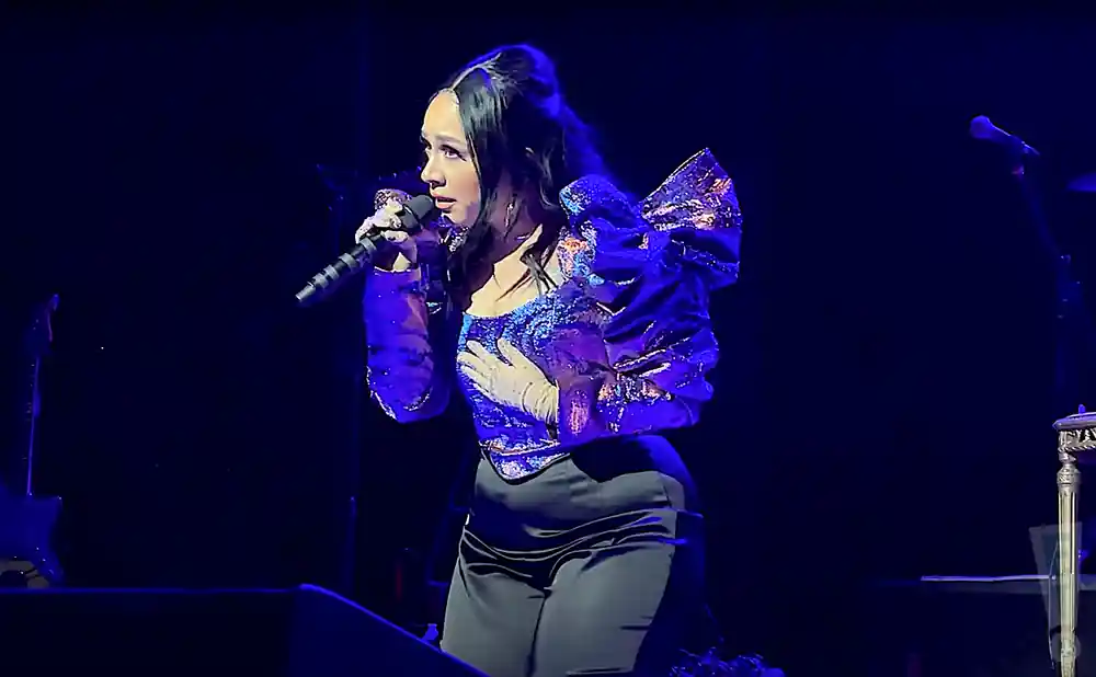 carla morrison performing on stage in sparkly outfit