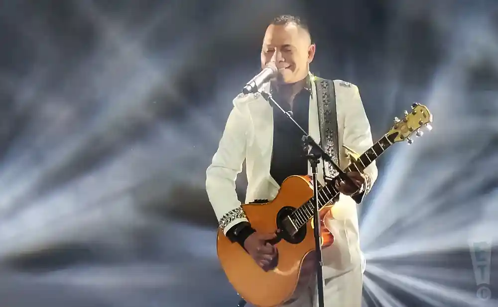 joe veras playing the guitar while singing live on stage