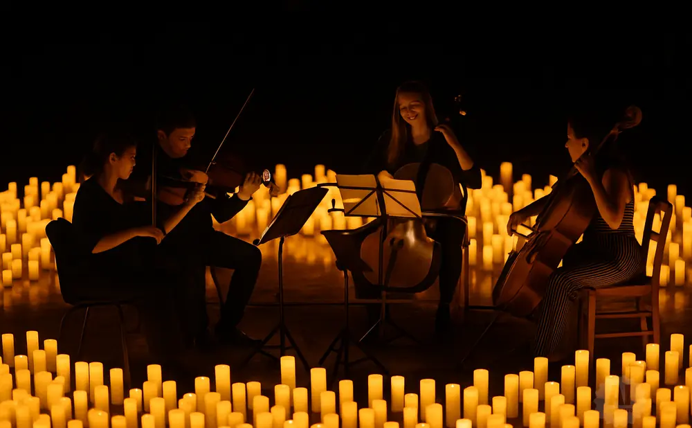 Musicians play violins and cellos by candlelight.