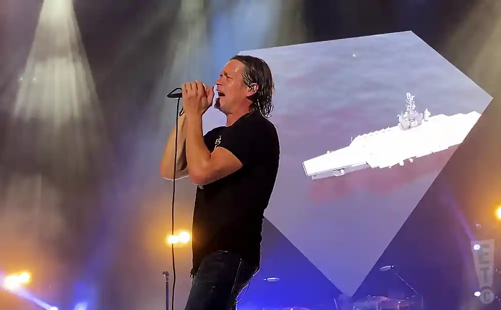 3 doors down lead singer performing on stage under blue and white lights