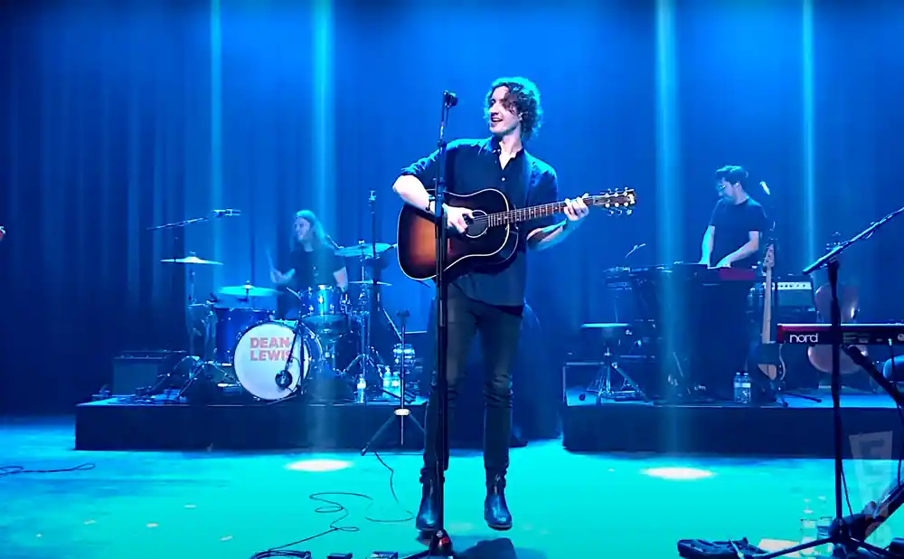 dean lewis playing the guitar in front of purple lights