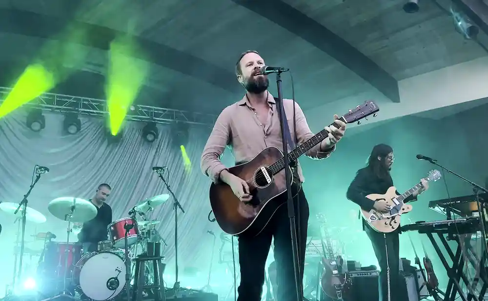 father john misty singing on stage while playing the guitar