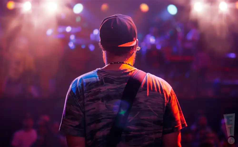 a rear view photo of johnny cosmic performing a concert on stage to a lively audience