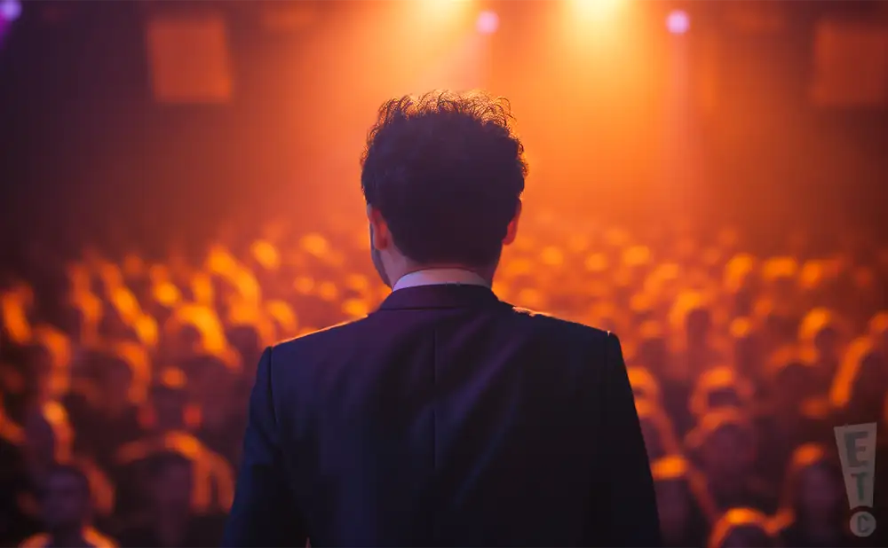 a rear view photo of kid francescoli performing a concert on stage to a lively audience