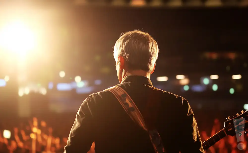 a rear view photo of nada surf performing a concert on stage to a lively audience