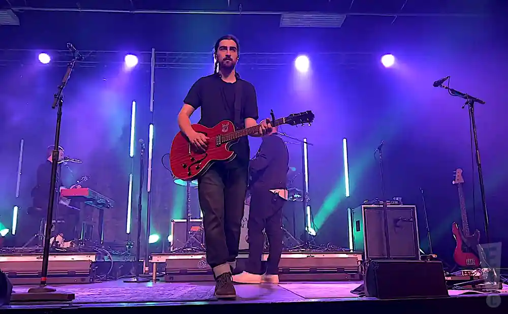 noah kahan playing live on stage in front of purple lights