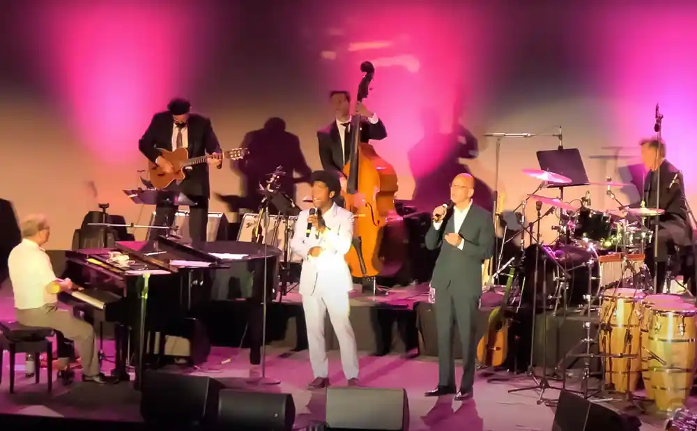 pink martini performing on stage with pink lights in athens greece