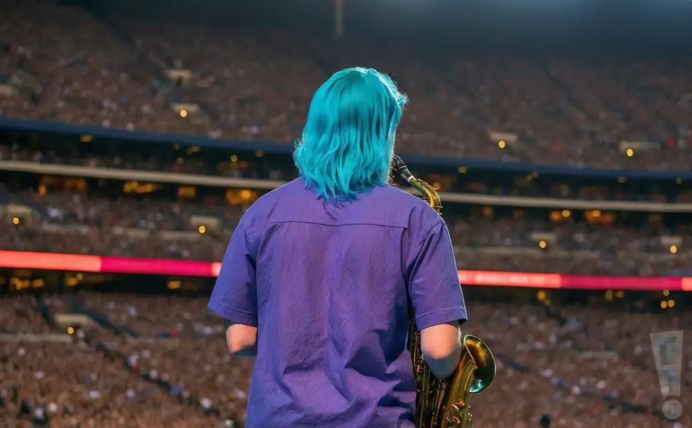 a rear view photo of too many zooz performing a concert on stage to a lively audience