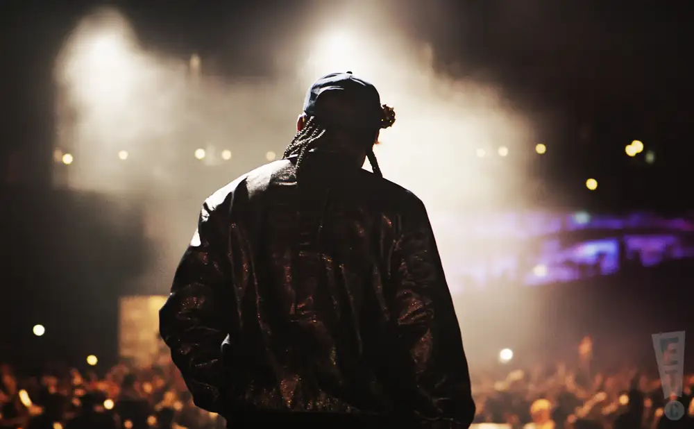 a rear view photo of jay-z performing a concert on stage to a lively audience
