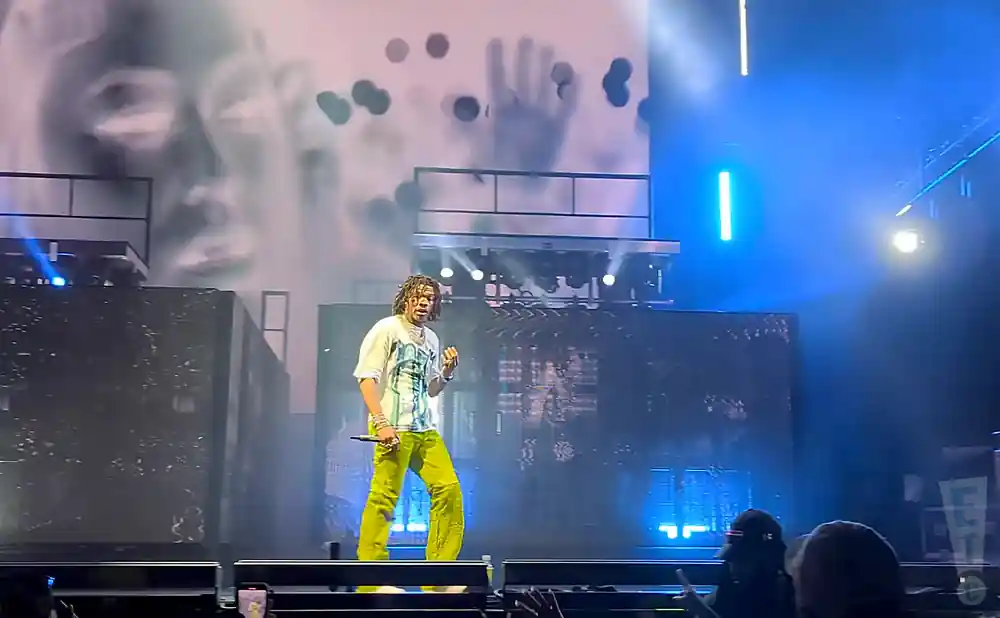 lil baby performing on stage wearing a white shirt and yellow pants
