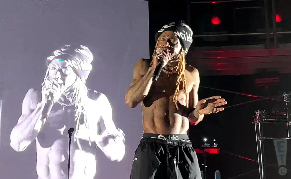 lil wayne rapping on stage with a screen behind him