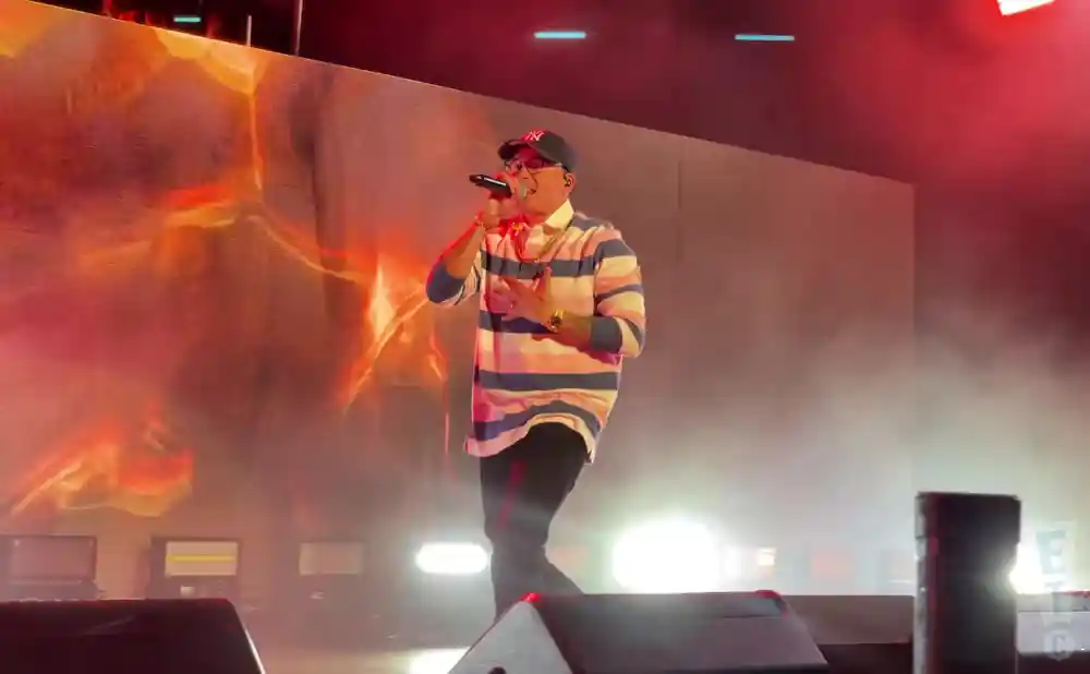 logic rapping on stage in stripped shirt